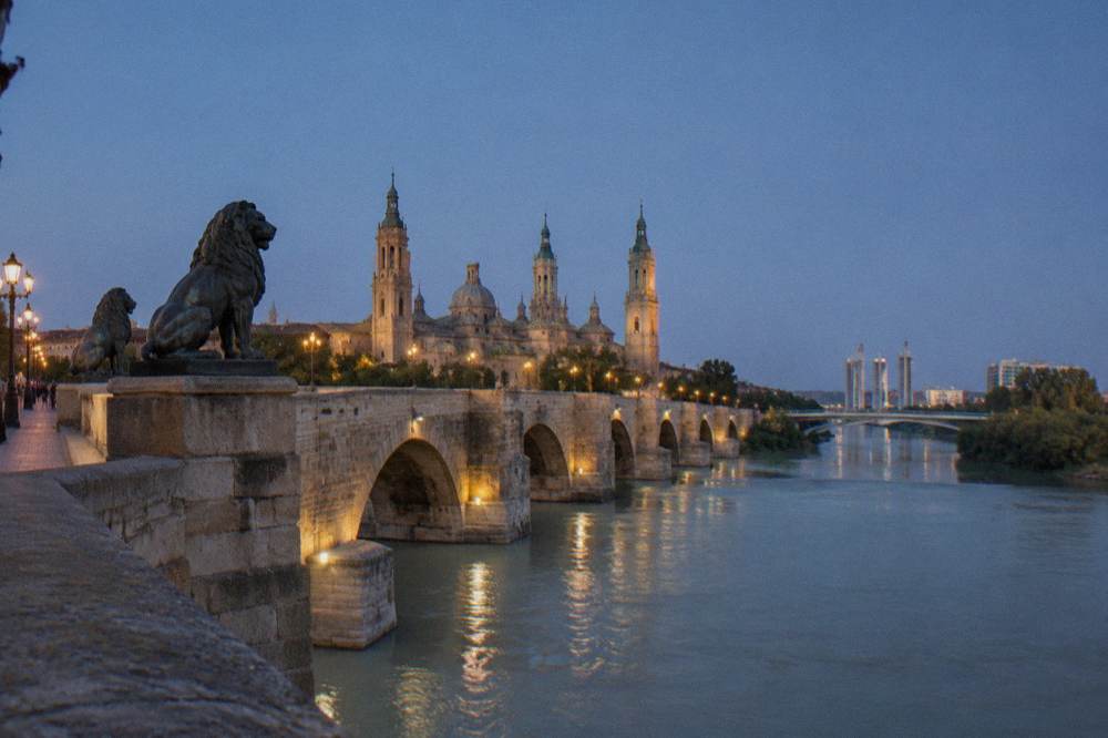 The modern bridge and towers of the Expo riverside seen across the Ranillas meander at dusk