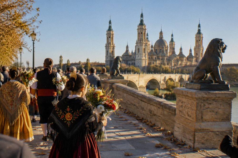 Participants in Aragonese regional dress carrying flowers during the Ofrenda de Flores along a crowded street