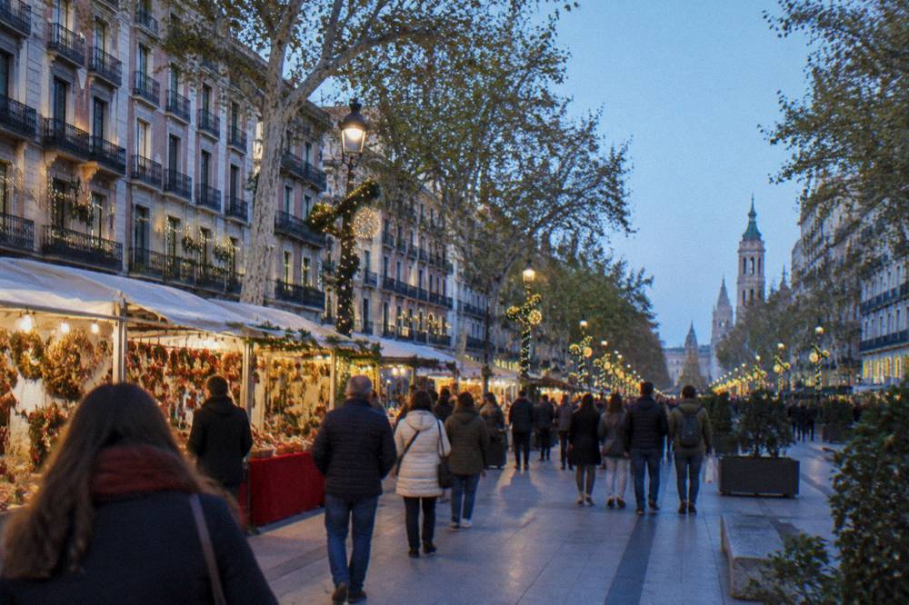 A festive street market with crowded stalls and decorated buildings in a Spanish city centre