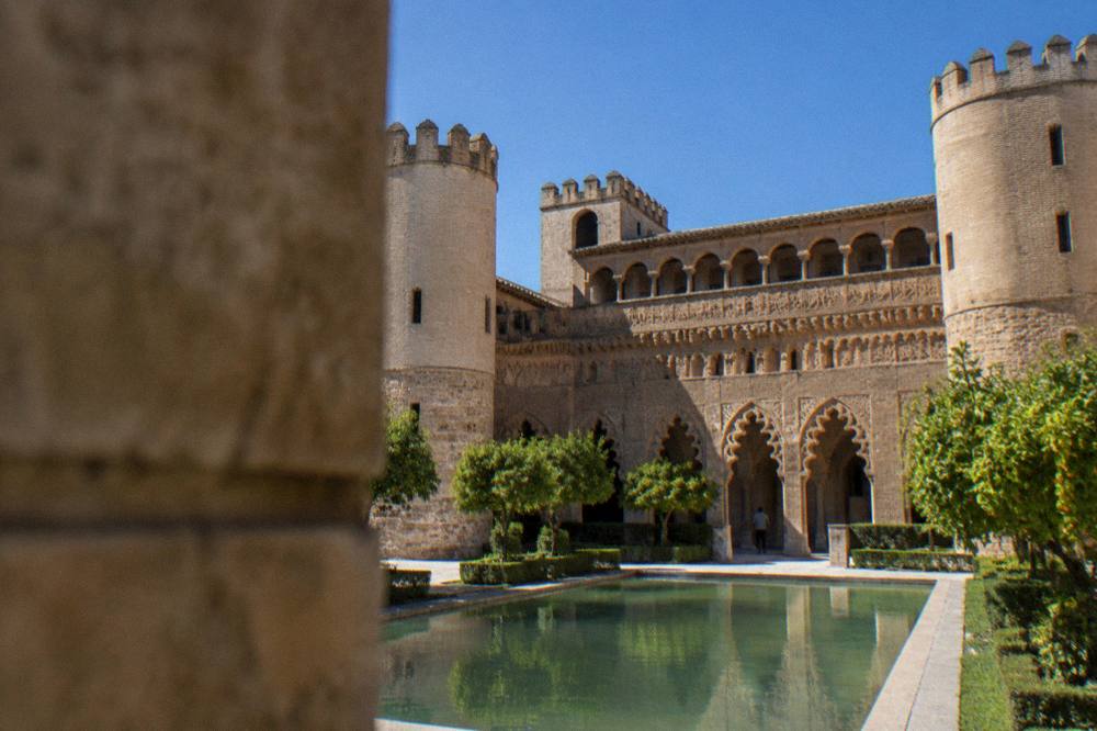 The ornate Mudéjar brick facade of the Aljafería palace under a clear sky