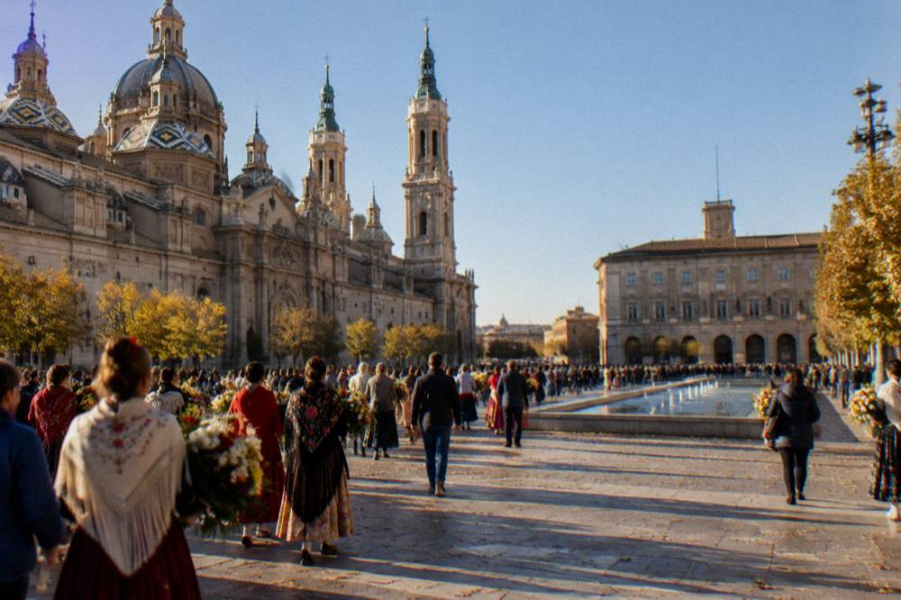Crowds in bright traditional dress filling a central Zaragoza street during the October flower offering