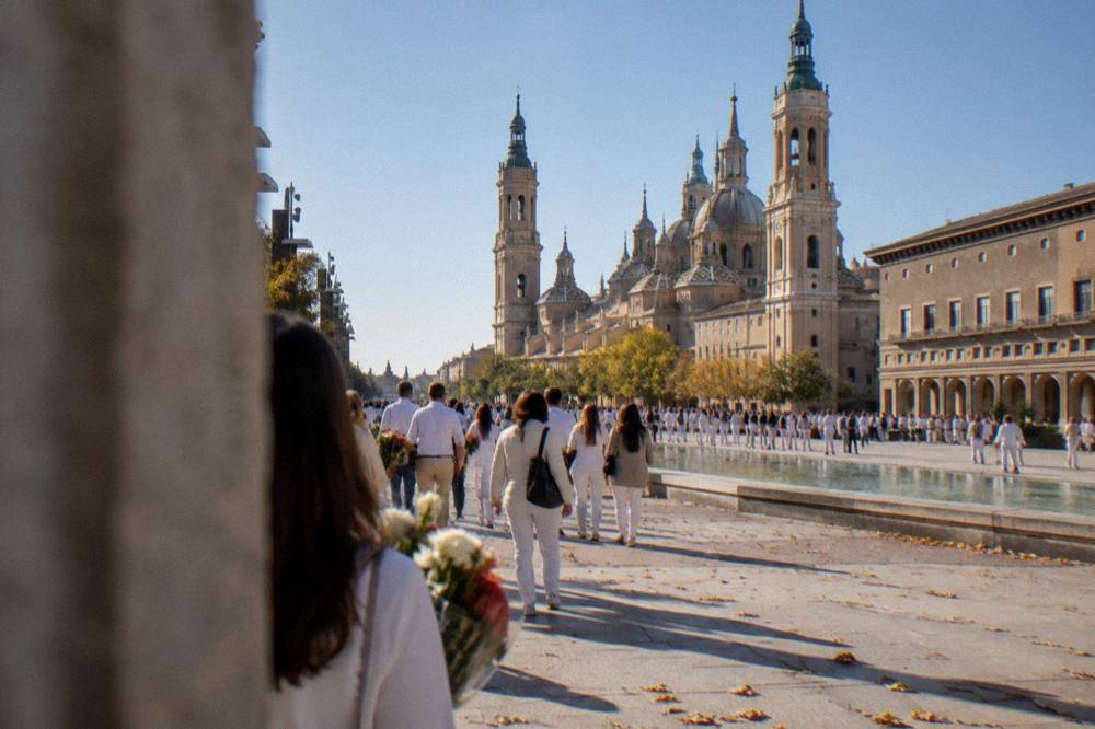 Crowds in white clothing filling a street during the Ofrenda de Flores in Zaragoza