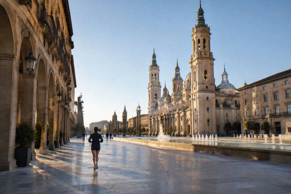 A quiet morning street of arched buildings in Zaragoza old town leading toward the Basílica del Pilar