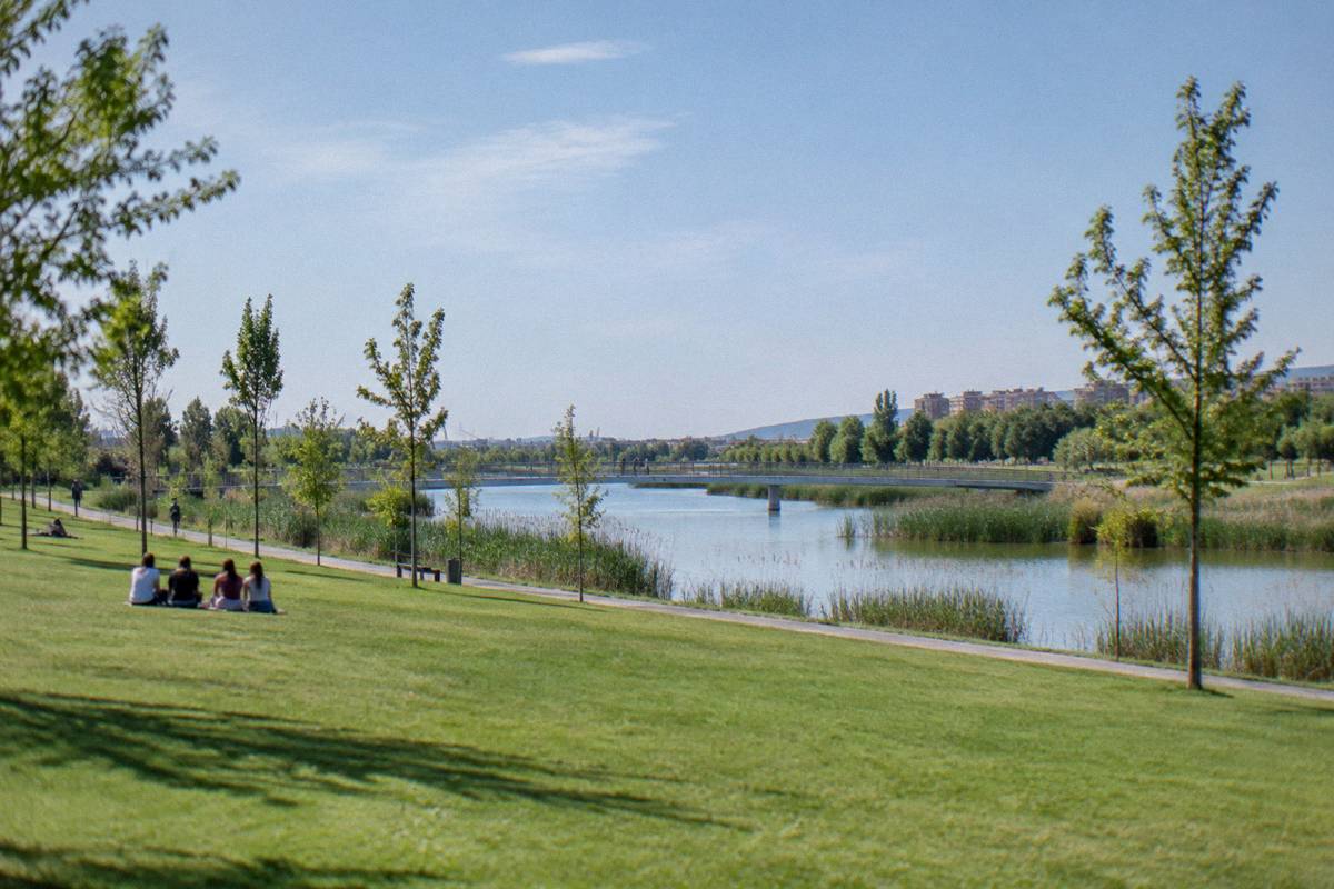 People walking along the Ebro riverside promenade beneath the basilica domes