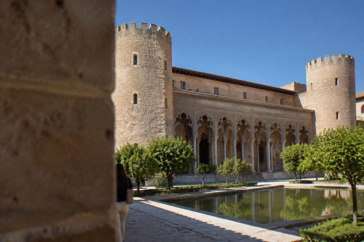 The Aljaferia Palace walls and corner towers against a blue sky