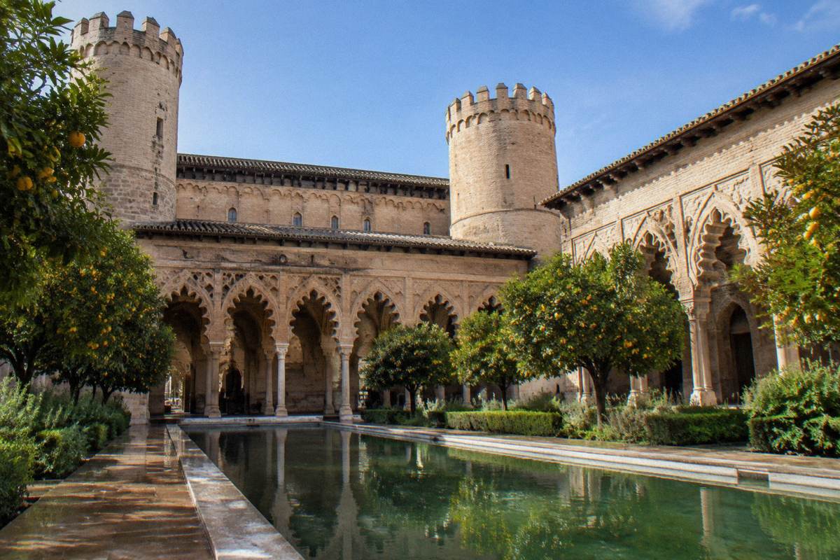 The Mudejar brick and stucco courtyard of the Aljaferia Palace in afternoon sun