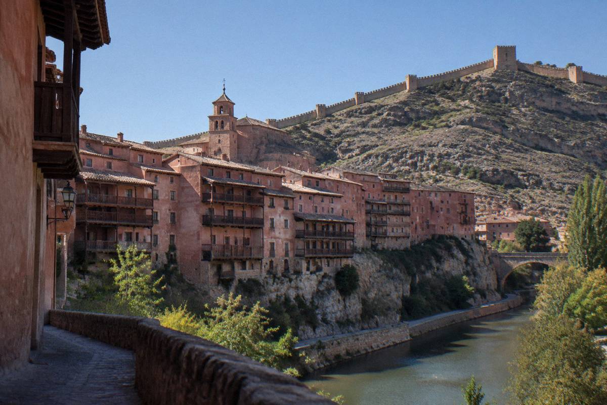 Pink-walled houses stacked on a rocky ridge above a river bend