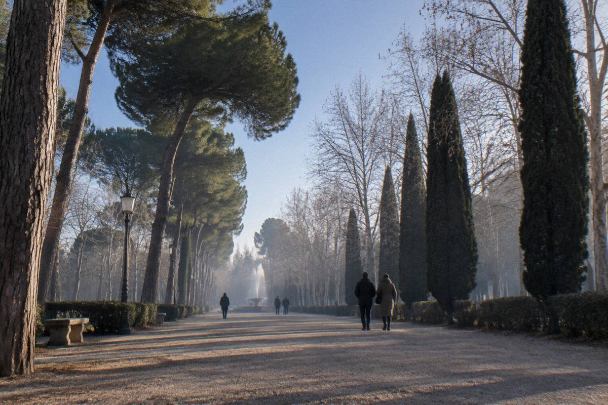 A person in a coat walking across an open riverside promenade in cold light