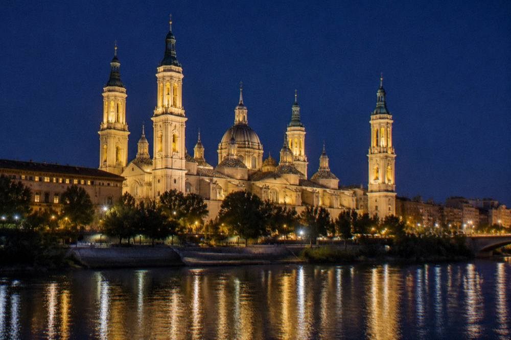 The floodlit Basílica del Pilar reflected in the Ebro river at night