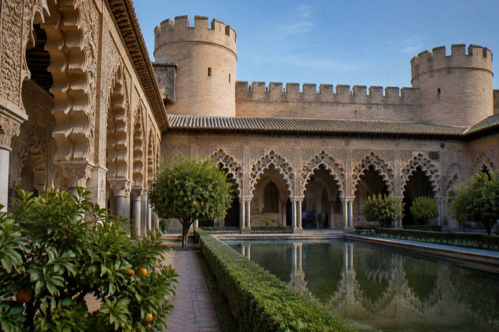 The ornate arches and carved stucco of the Aljafería palace courtyard