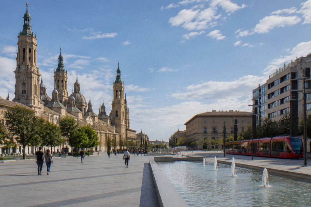 A red Zaragoza tram passing modern buildings along a city avenue
