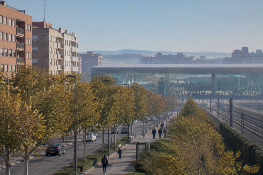 The modern glass facade of Zaragoza-Delicias train station with travellers moving across the concourse