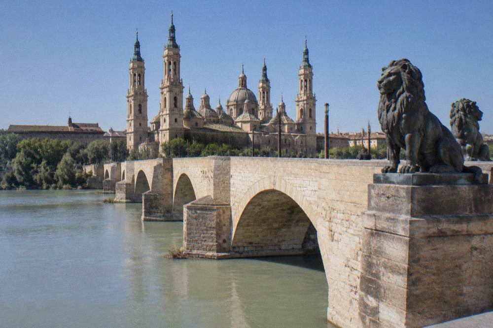 The stone arches of the Puente de Piedra bridge over the Ebro with the basilica's domes behind