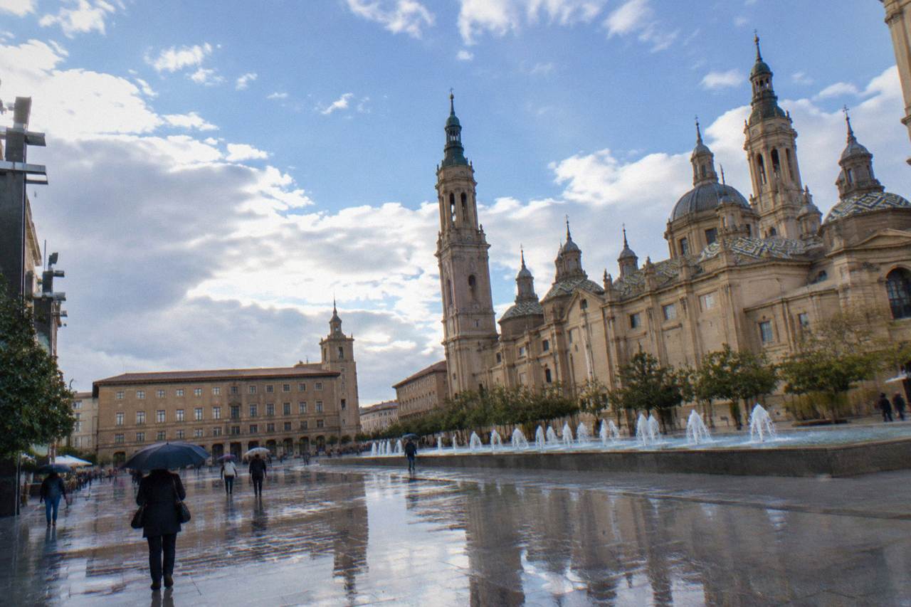 Wet stone street in the old town of Zaragoza with umbrellas and reflections on the paving