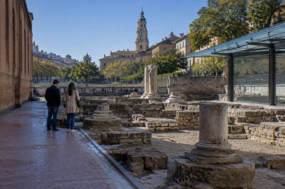 Two people looking at Roman stone remains inside one of the Caesaraugusta museum sites