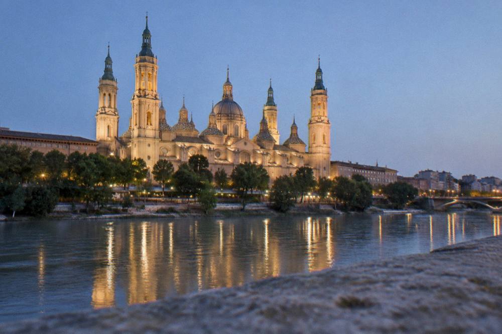 The floodlit Basílica del Pilar seen at night from across the Ebro river