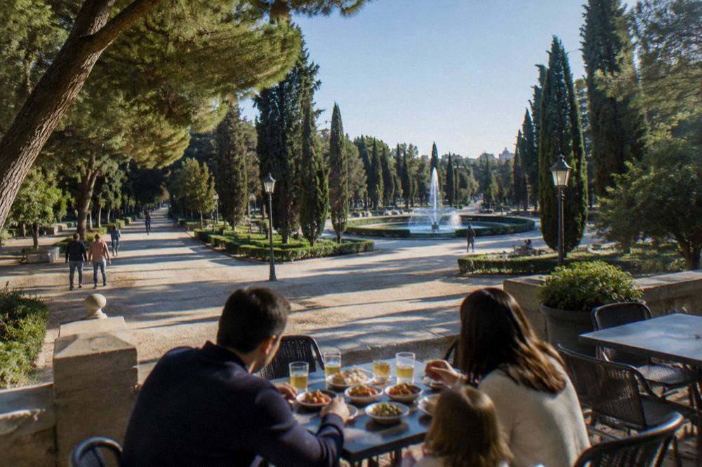 A family sharing a plate of small tapas dishes at an outdoor cafe table in an old square